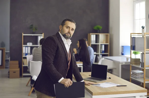 Retrato de alto ejecutivo serio de negocios de pie cerca de escritorio en la oficina moderna — Foto de Stock