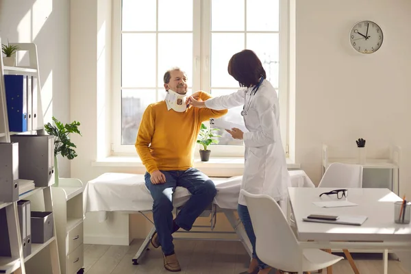 Dokter onderzoekt patiënt met nek halsband in revalidatie kliniek kantoor — Stockfoto