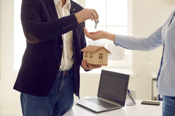 Recorte de agente de bienes raíces sosteniendo modelo de casa pequeña y dando la llave al cliente —  Fotos de Stock