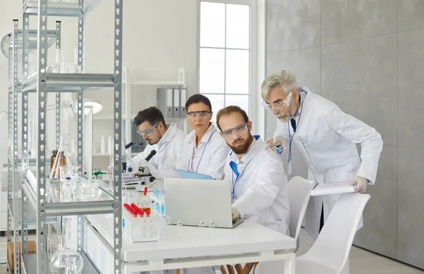 Wetenschappelijke groep discussiëren kijken naar laptop scherm werken in het laboratorium — Stockfoto
