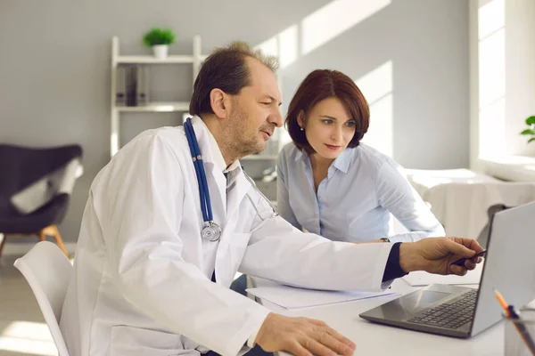 Mulher ouvindo médico e olhando para a tela do laptop com resultados de triagem de saúde — Fotografia de Stock