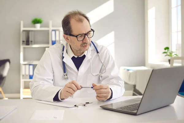 Médico ter videochamada on-line consulta remota no laptop no escritório da clínica — Fotografia de Stock