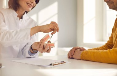 Diş hekimi insan çene plastik modeli üzerinde hastaya yakın çekim görüntüsü problemi gösteriyor