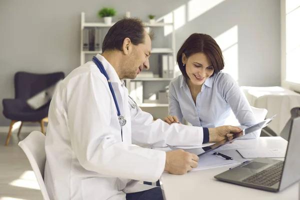 Donna felice ascoltando il medico e guardando la risonanza magnetica o la scansione a raggi X con buon risultato — Foto Stock