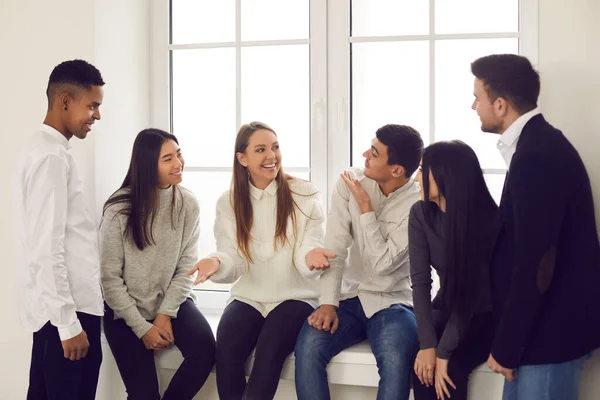 Grupp glada unga multiracial medarbetare eller vänner talar om roliga saker och ler — Stockfoto