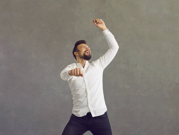 Een vrolijke vrolijke jongeman dansend gangnam stijl tegen een grijze studio achtergrond — Stockfoto