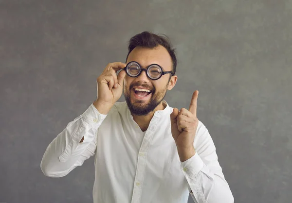 Grappig gek uitziende nerd in bril heeft een briljant idee en wijst met zijn vinger omhoog — Stockfoto