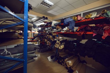 Ayakkabı ya da giysi fabrikasında kumaş ve deri rulo dolu raflar.