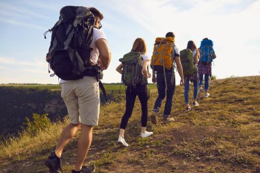 Büyük sırt çantalı bir grup turist dağın zirvesine tırmanıyor..