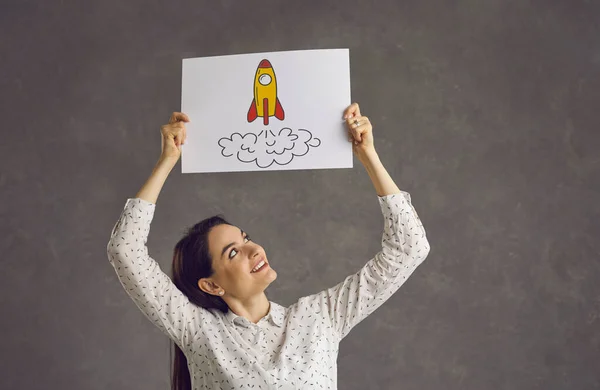 Mujer feliz sosteniendo imagen de cohete como concepto de innovación y éxito en la educación y los negocios — Foto de Stock