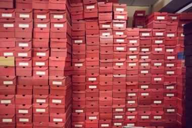 Fabrika deposunda üst üste dizilmiş büyük kırmızı karton kutular.