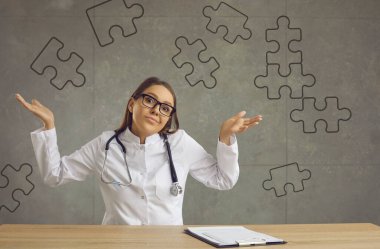 Kafası karışmış doktor, gri arka planda oturan omuzlarını yarım kalmış yapbozla silkeliyor.