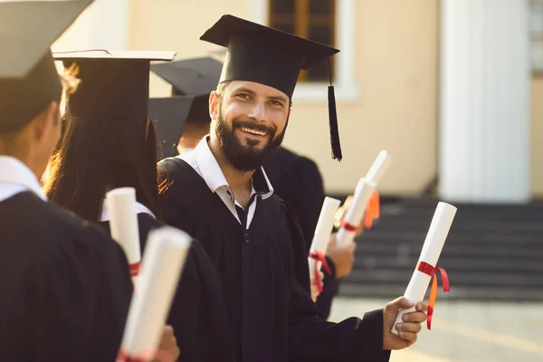 Egy boldog fiatal diplomás portréja, aki diplomáját a diplomaosztó ünnepségen szerezte. — Stock Fotó