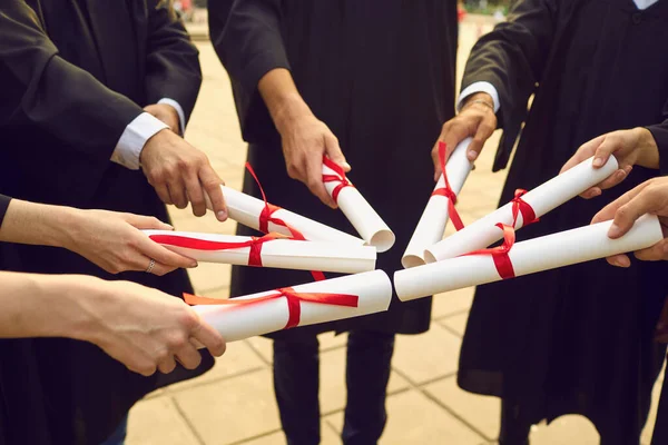 Hands of university graduates holding dimplomas with honors in sun shape — 스톡 사진