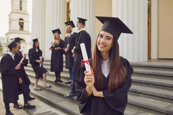 Boldog pozitív csinos lány egyetemi diplomás álló kezében diploma a kezében — Stock Fotó