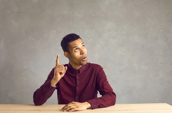 Jonge afrikaanse amerikaanse man zitten aan tafel met opgeheven vinger hebben idee — Stockfoto