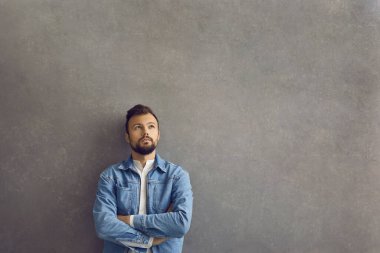 Düşünen yüzü gri beton arka planda duran yakışıklı beyaz adam..