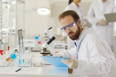 Laboratuvarda test örneğiyle çalışan tıbbi erkek eczacı.