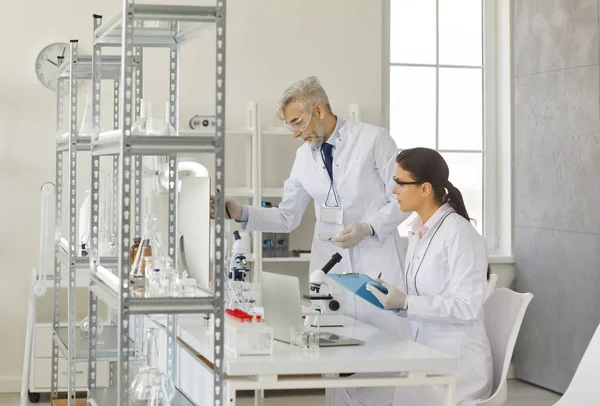 Dwóch różnych naukowców przeprowadzających eksperymenty w nowoczesnym laboratorium chemicznym — Zdjęcie stockowe
