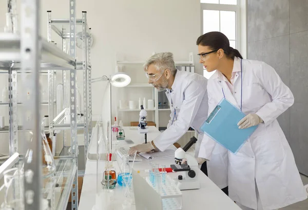 Cientista masculino e feminino analisando resultados na tela do computador em laboratório — Fotografia de Stock