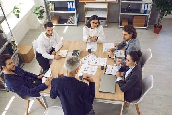 Équipe de travailleurs sérieux à l'écoute de cadres supérieurs assis autour de la table dans une réunion d'entreprise — Photo