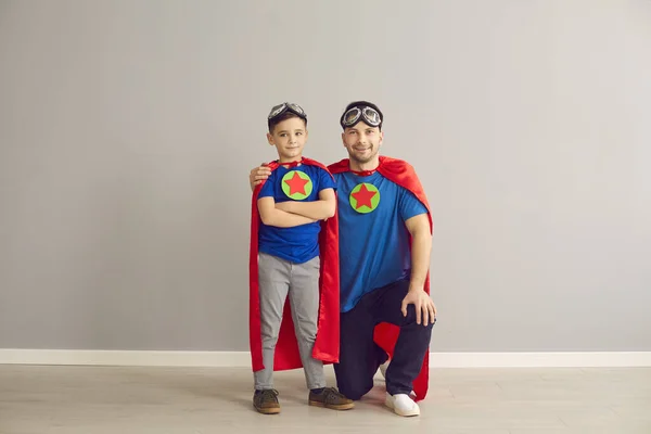 Otec a syn v kostýmu superhrdiny při pohledu na portrét fotoaparátu — Stock fotografie