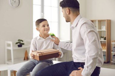 Sevgi dolu bin yıllık baba ve evde paketlenmiş hediye kutusu olan sevimli küçük oğul.