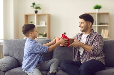Tatlı çocuk tatilde babasına tebriklerini sunuyor ve ona bir hediye kutusu veriyor..