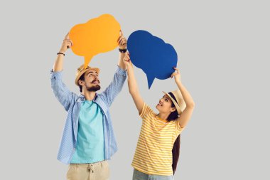 Two happy tourists holding conversation bubbles isolated on light gray background
