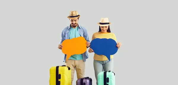 Δύο ευχαριστημένοι τουρίστες με ταξιδιωτικές βαλίτσες στέκεται στο στούντιο κρατώντας φούσκες συνομιλία — Φωτογραφία Αρχείου