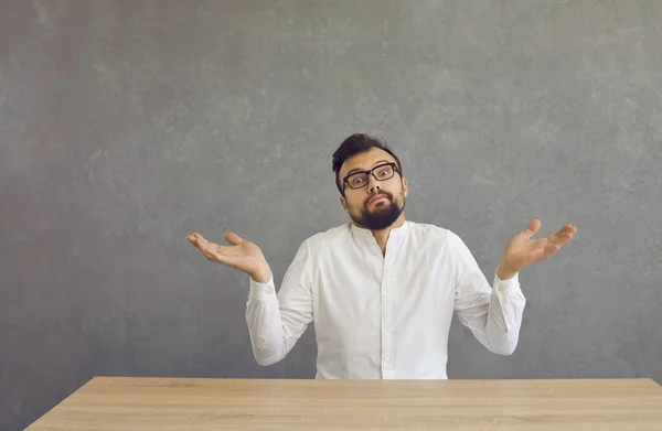 Confused young bearded man shrugs and spreads his arms with a dumb and puzzled expression. — Stockfoto