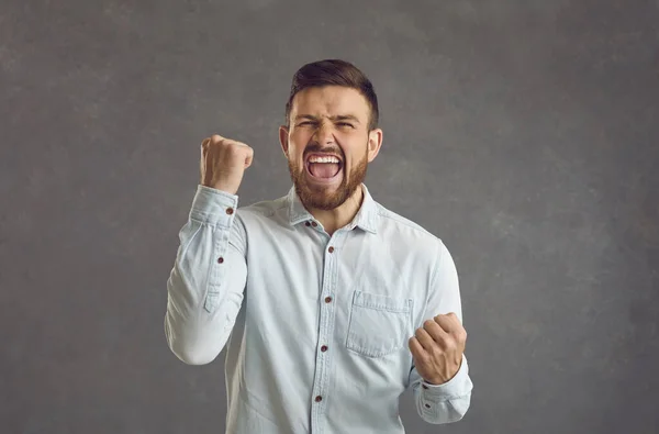 Portrait of an emotional young man laughing and shouting with clenched fists celebrating victory. — Stockfoto