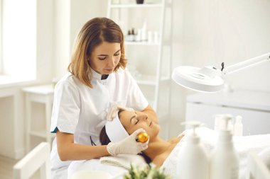 Cildiyeciler yong kadını için fonoforez yüz prosedürü hazırlıyorlar.