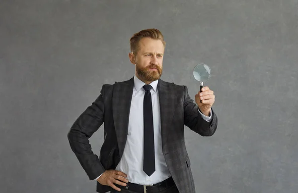 Studio portrait shot of concentrated businessman in suit with magnifier — Foto de Stock