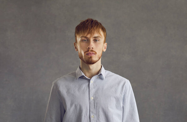 Serious red-haired man headshot studio face portrait over grey background