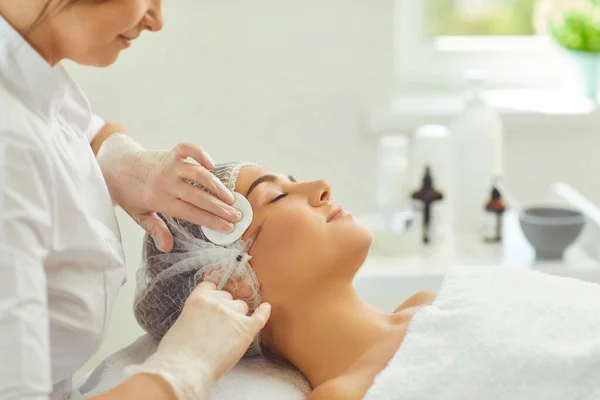 Mujer sonriente recibiendo la inyección de piel anti-envejecimiento de belleza a la mejilla de dermatólogo profesional —  Fotos de Stock