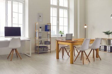 Modern masalar, sandalyeler ve raflarla dolu parlak bir ofis manzarası.