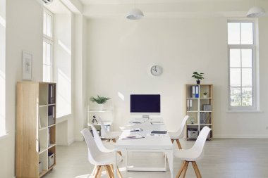 Interior of cozy light boardroom with big table, modern chairs and desktop computer