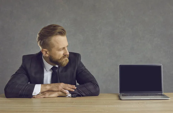 Caucasian businessman sitting at table and looking at laptop black screen — ストック写真