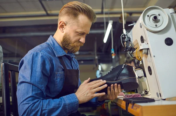 Trabalhador sentado à mesa com máquina de costura sapato e verificar a qualidade do calçado — Fotografia de Stock