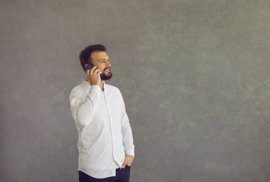 Neşeli ve gülümseyen beyaz adam cep telefonunda keyifli bir konuşma yapar..