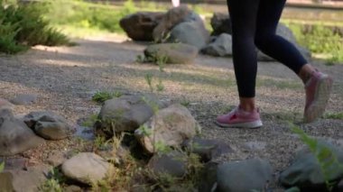 Yürüyüşçü kadın ormanda yürüyor, bacaklarına bakıyor, sportif ve sağlıklı bir yaşam tarzı var.