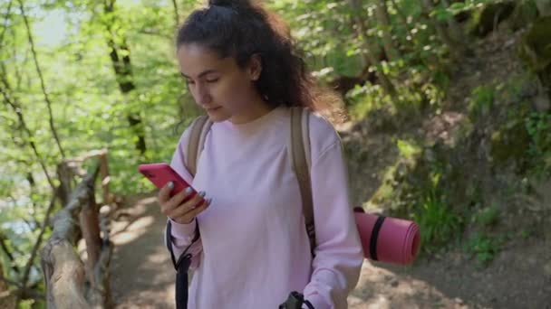 Giovane donna con smartphone nella foresta, escursioni e navigazione con mappa elettronica — Video Stock