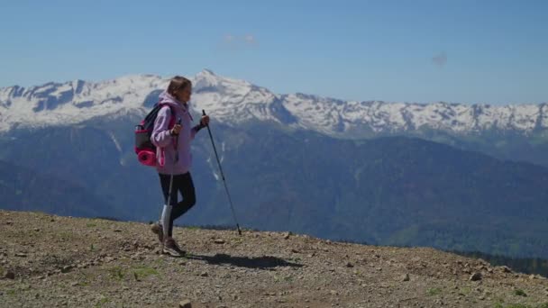 Sırt çantalı bir kadın dağın tepesinde yürüyüş yapıyor. — Stok video