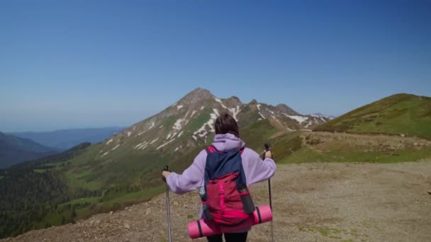 Στην κορυφή του βουνού, γυναίκα πεζοπόρος σηκώνει τα χέρια και θαυμάζοντας τη φύση από ψηλά, πίσω όψη — Αρχείο Βίντεο