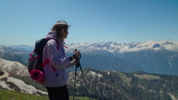 Trekking in de bergen, jonge vrouwelijke wandelaar met rugzak en wandelstokken — Stockvideo