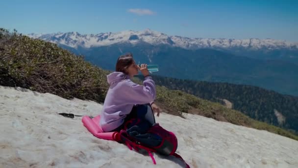 Unavený batohem mít odpočinek a pití po lezení na horu — Stock video