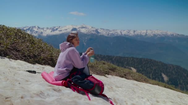 Reizen in Highland, vrouw rust na wandelen en klimmen op de top van de besneeuwde berg — Stockvideo