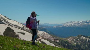 Kadın gezgin dağın tepesinde su içiyor, yorgun yürüyüşçü dinleniyor.
