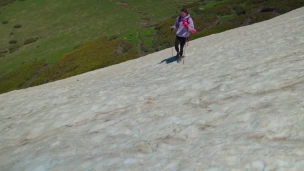 女の子ハイカーは慎重に雪の丘の中腹に歩く — ストック動画